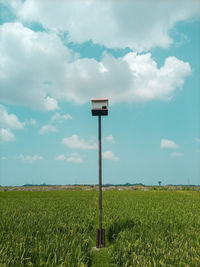 Road sign on field against sky