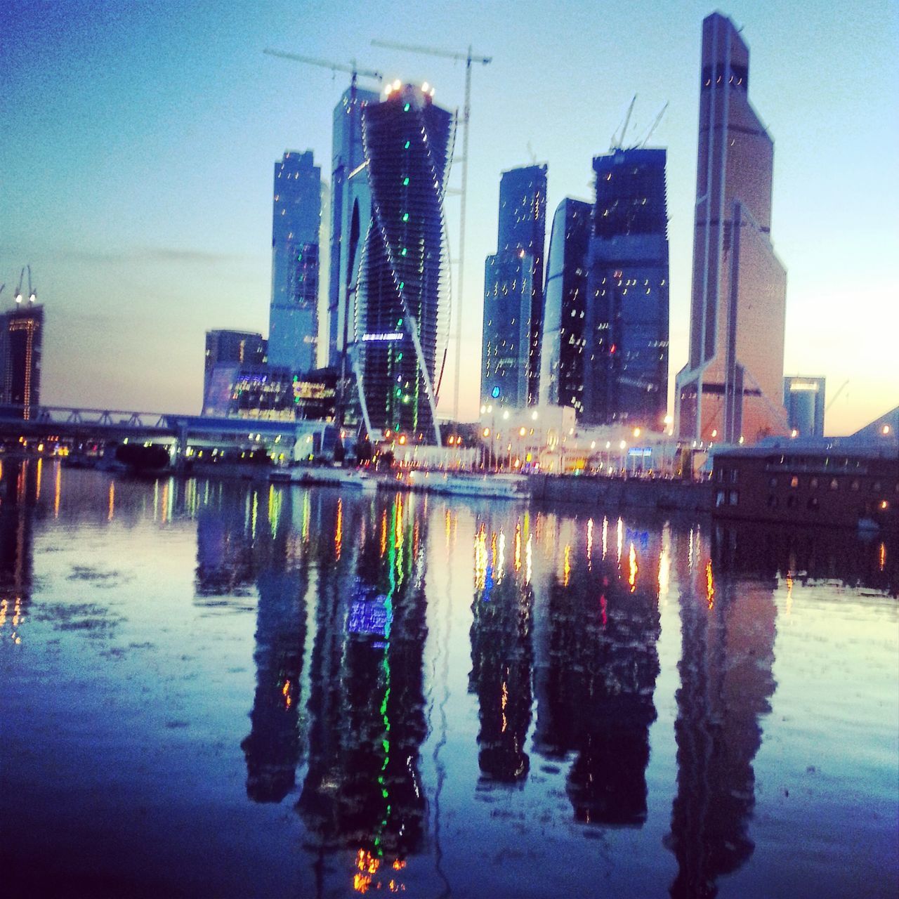 building exterior, architecture, reflection, built structure, water, city, skyscraper, waterfront, modern, tall - high, urban skyline, illuminated, tower, sky, office building, cityscape, river, development, building, dusk