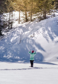 Rear view of person standing on snow covered field against sky