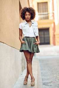 Full length portrait of woman standing against wall