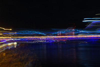 Illuminated light trails on water against sky at night