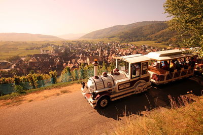 People traveling in commercial vehicle on road against town