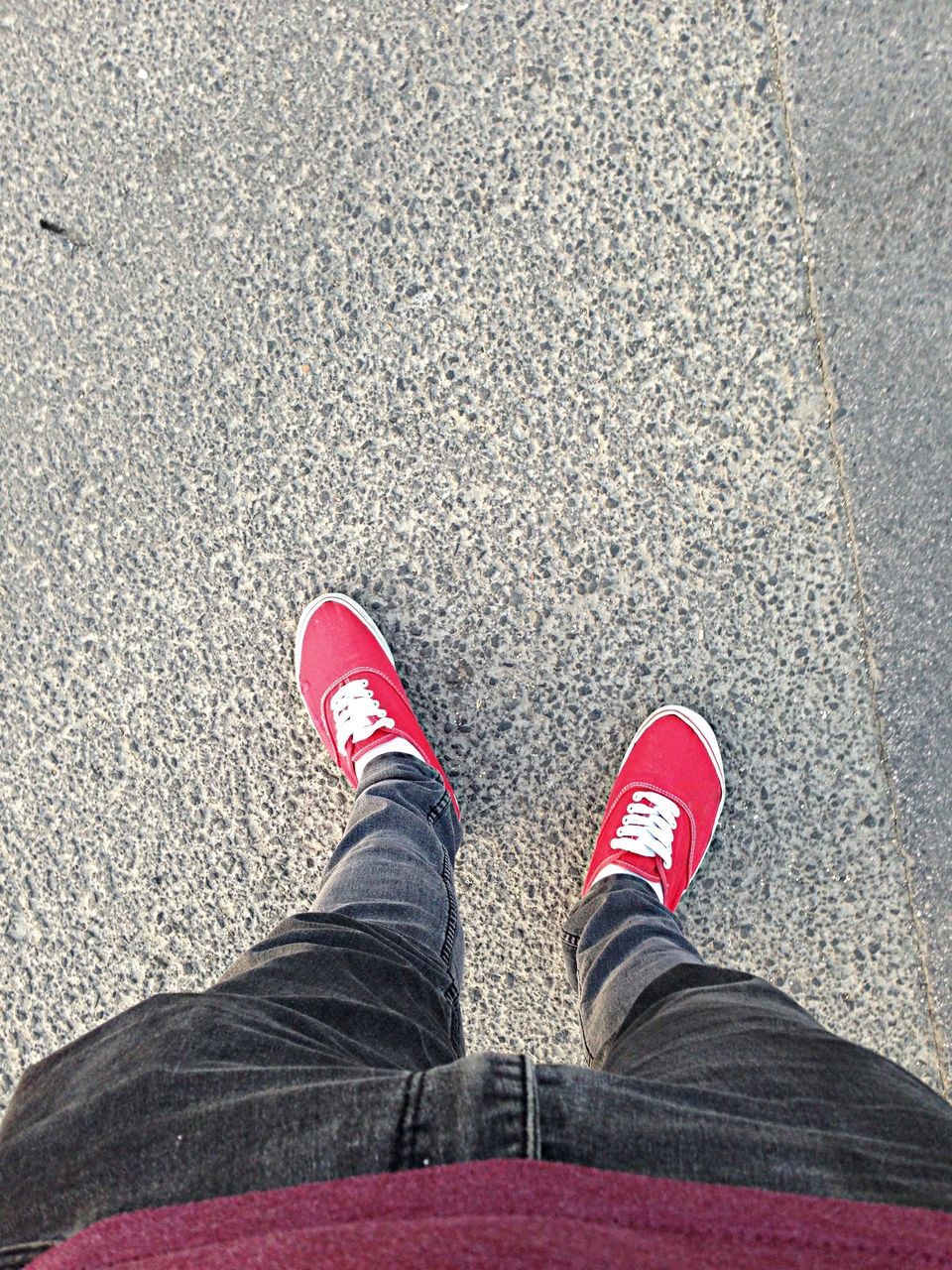 low section, person, shoe, personal perspective, standing, lifestyles, footwear, red, street, human foot, high angle view, jeans, men, leisure activity, road, canvas shoe, casual clothing