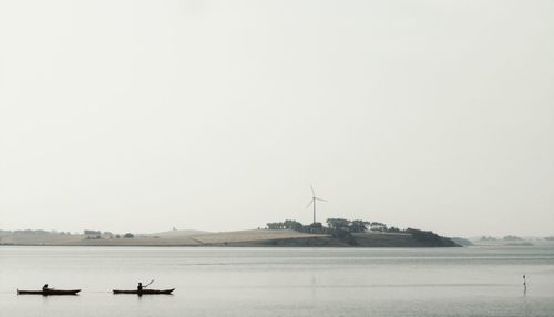 Boats in sea against clear sky