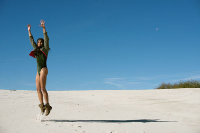 Woman standing on beach against blue sky