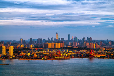 City at waterfront against cloudy sky