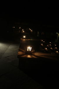 Illuminated lights on street by building at night