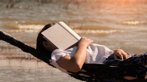 Close-up of girl covering face while resting on hammock