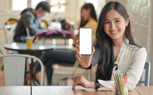Portrait of young woman using smart phone in restaurant