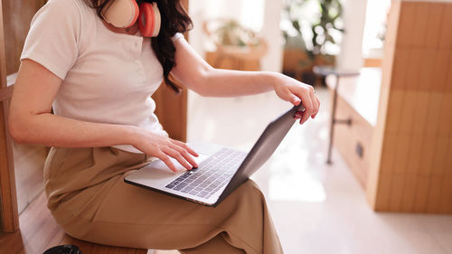 Midsection of woman using laptop at home