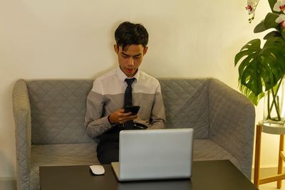 Young man using laptop while sitting on table