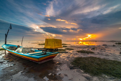 Boats moored on sea against sky during sunset