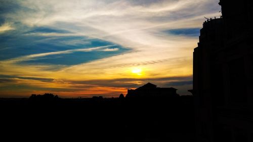 Silhouette of buildings against cloudy sky