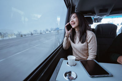 Young woman using mobile phone while sitting in car