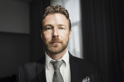 Portrait of confident businessman standing in hotel room