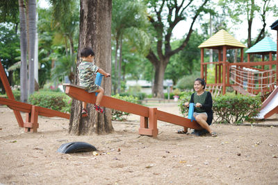 Mother and son playing on seesaw at playground