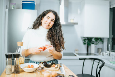 Portrait of smiling young woman having food at home