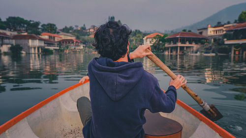 Rear view of man holding boat in river