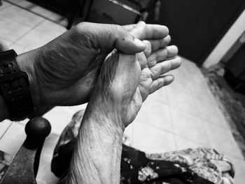 Cropped image of man holding senior woman hand at home