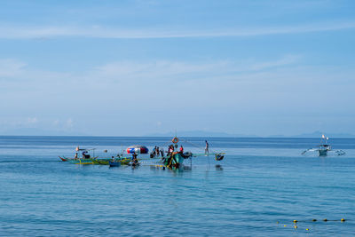 People in sea against sky