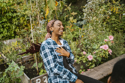 Cheerful young woman laughing while sitting in urban farm