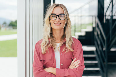 Portrait of young woman standing against wall