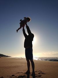 Woman standing on beach at sunset