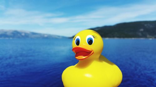 Close-up of rubber duck against blue river on sunny day