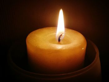 Close-up of illuminated candle in darkroom