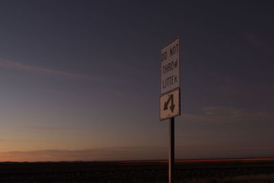 Low angle view of road sign against sky at sunset