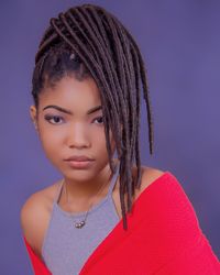 Portrait of beautiful young woman with dreadlocks against colored background