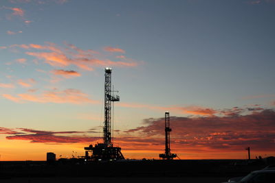 Low angle view of silhouette factory against sky during sunset