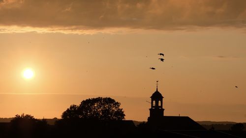 Silhouette building against sky during sunset