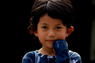 Portrait of cute boy against black background