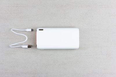 White power bank for charging smartphones and various digital devices on a grey background close-up