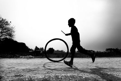 Side view of silhouette boy playing on field against clear sky