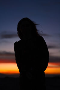 Rear view of silhouette woman standing against sky during sunset