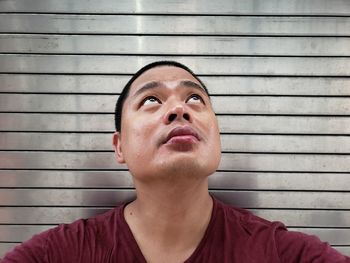 Portrait of young man looking away against wall