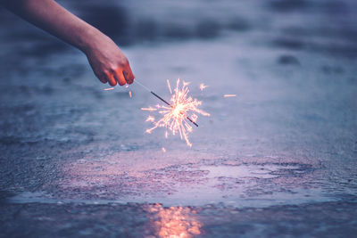 Close-up of hand holding sparkler at beach
