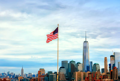 Flags on modern buildings in city against cloudy sky