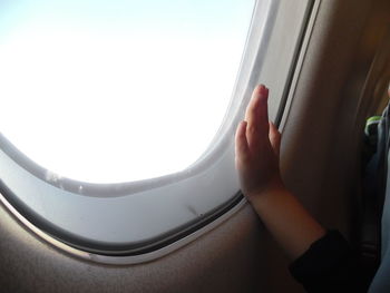 Cropped image of child hand on airplane window