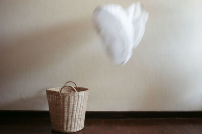Blurred motion of cloth above wicker basket on floor at home