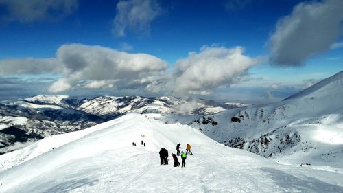 People on snowcapped mountains against sky