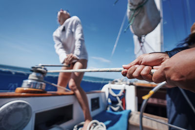 People holding sailboat in sea against sky