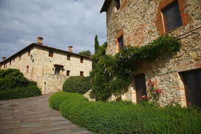 Footpath by old building against sky