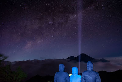 Rear view of people wearing warm clothing against star field at night