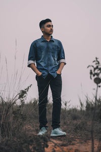 Full length of thoughtful young man standing on field