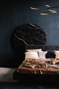Black and gold bed with a black covered in brown sheets and pillows in modern bedroom