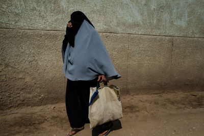 Rear view of woman walking against wall