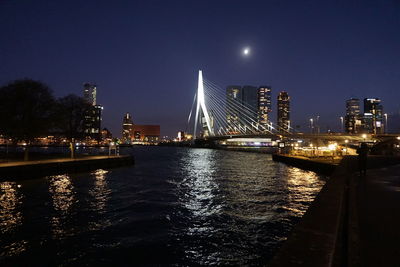 Illuminated bridge over river against sky at night